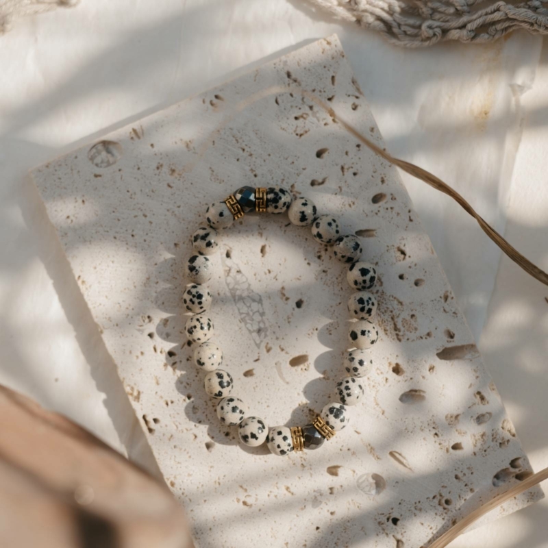 Bransoletka Guardian z jaspisu dalmatyńskiego na tle kamienia w promieniach słońca – energia ziemi i męska siła.